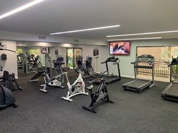 A gym with a variety of exercise equipment including treadmills, stationary bikes, and weight machines.